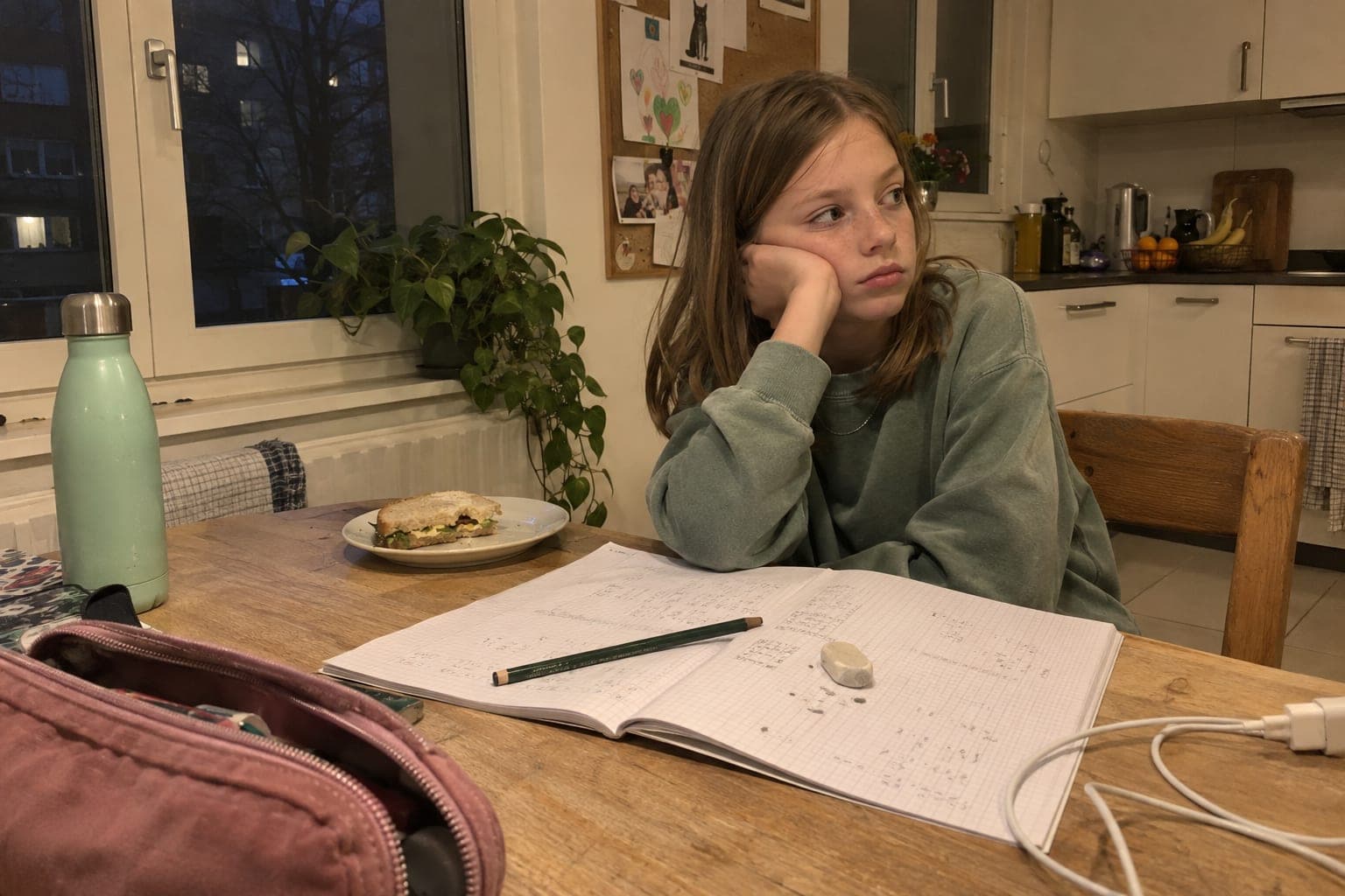 Mädchen sitzt frustriert über den Hausaufgaben am Küchentisch