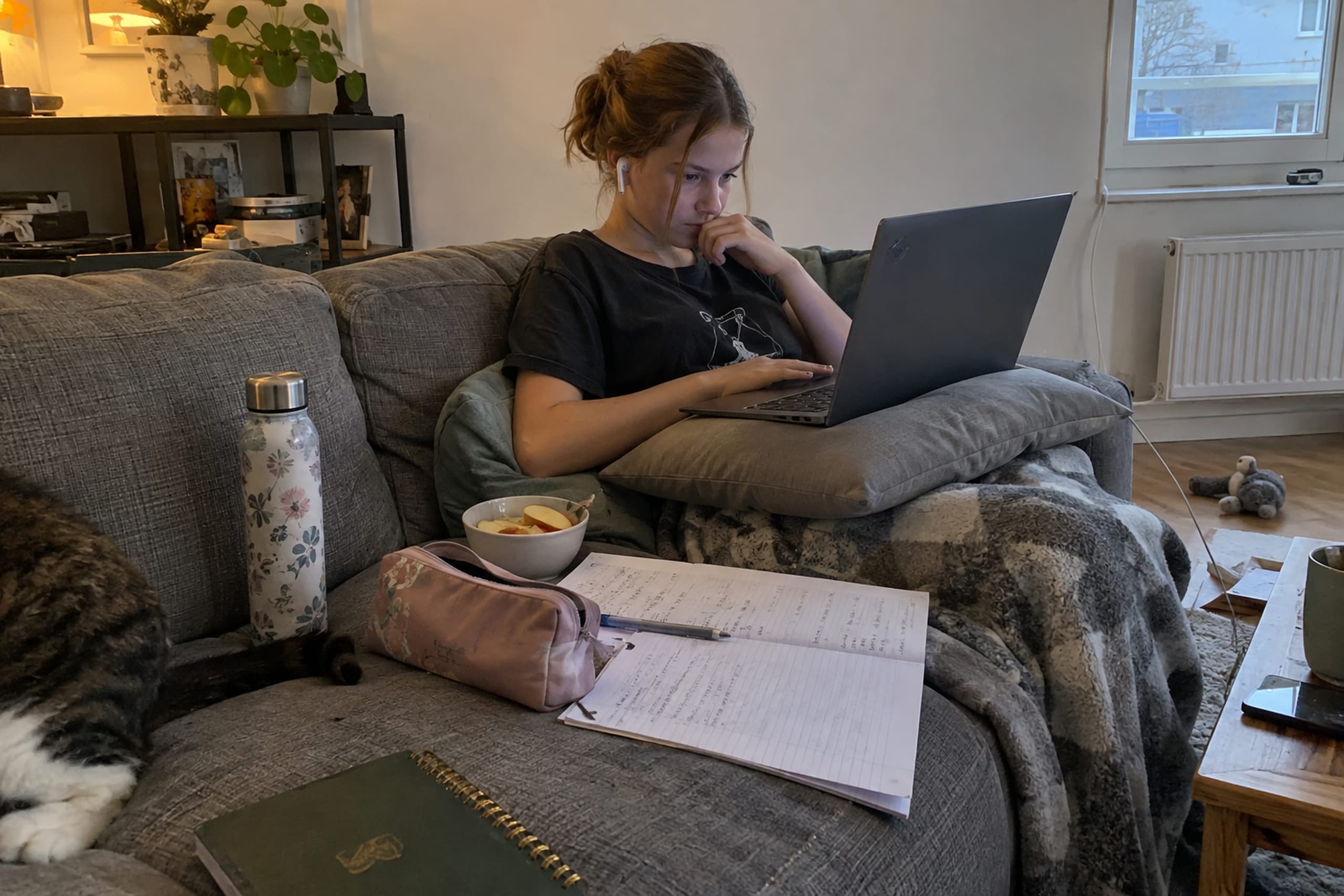 Schülerin auf dem Sofa mit Laptop und englischer Vokabelliste